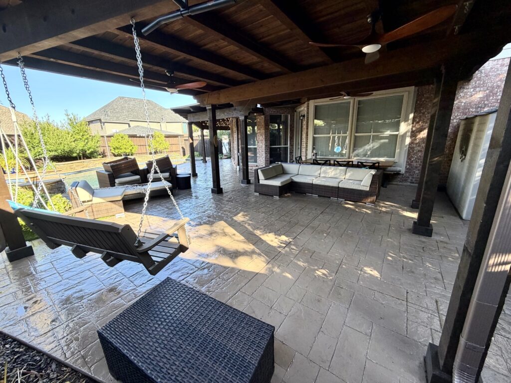 Spacious outdoor patio with seating and a swing under a wooden pergola.