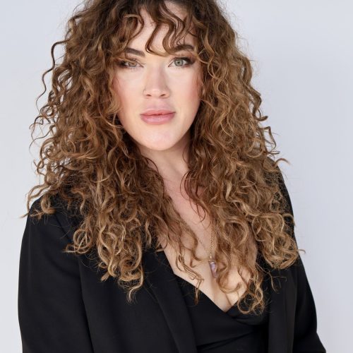 Portrait of a woman with curly hair wearing a black blazer.